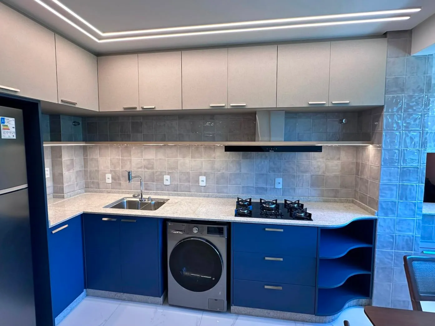 Cozinha planejada em azul-marinho com bancada em granito claro e cooktop