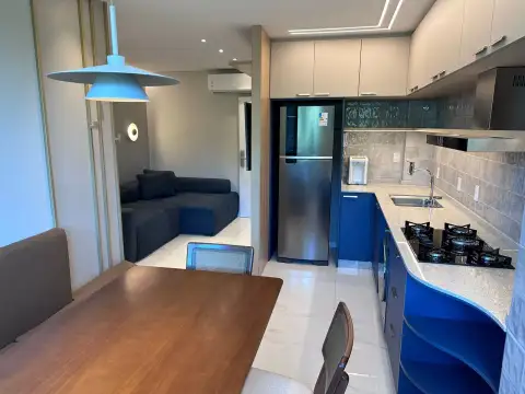 Cozinha planejada azul integrada à sala de estar com geladeira inox