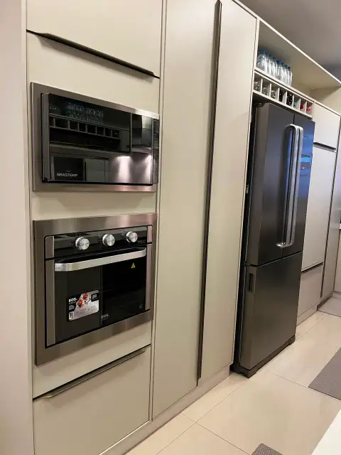 Detalhe de forno e micro-ondas de embutir junto à geladeira inox