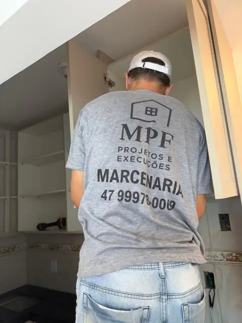 Profissional da equipe MPF organizando armário planejado de cozinha