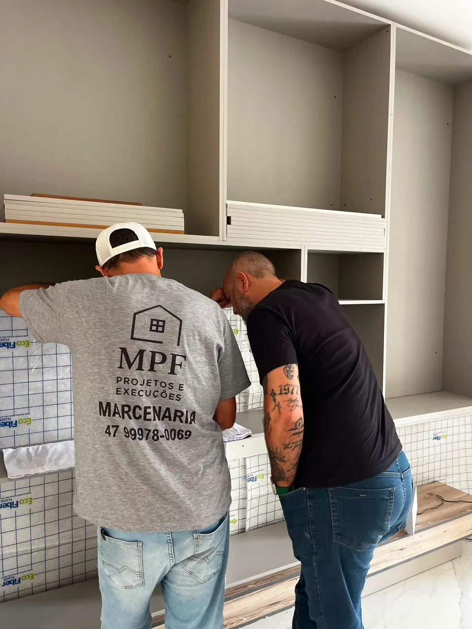 Equipe MPF Projetos e Execuções instalando estante planejada em obra