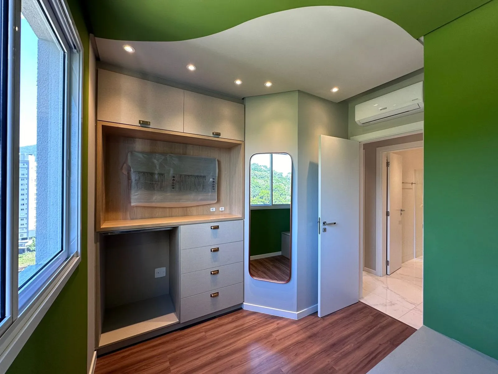 Closet planejado com portas em laca, nicho para TV e espelho emoldurado em cobre