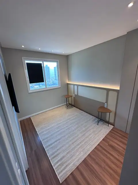 Quarto vazio com tapete, piso de madeira e cabeceira integrada em marcenaria