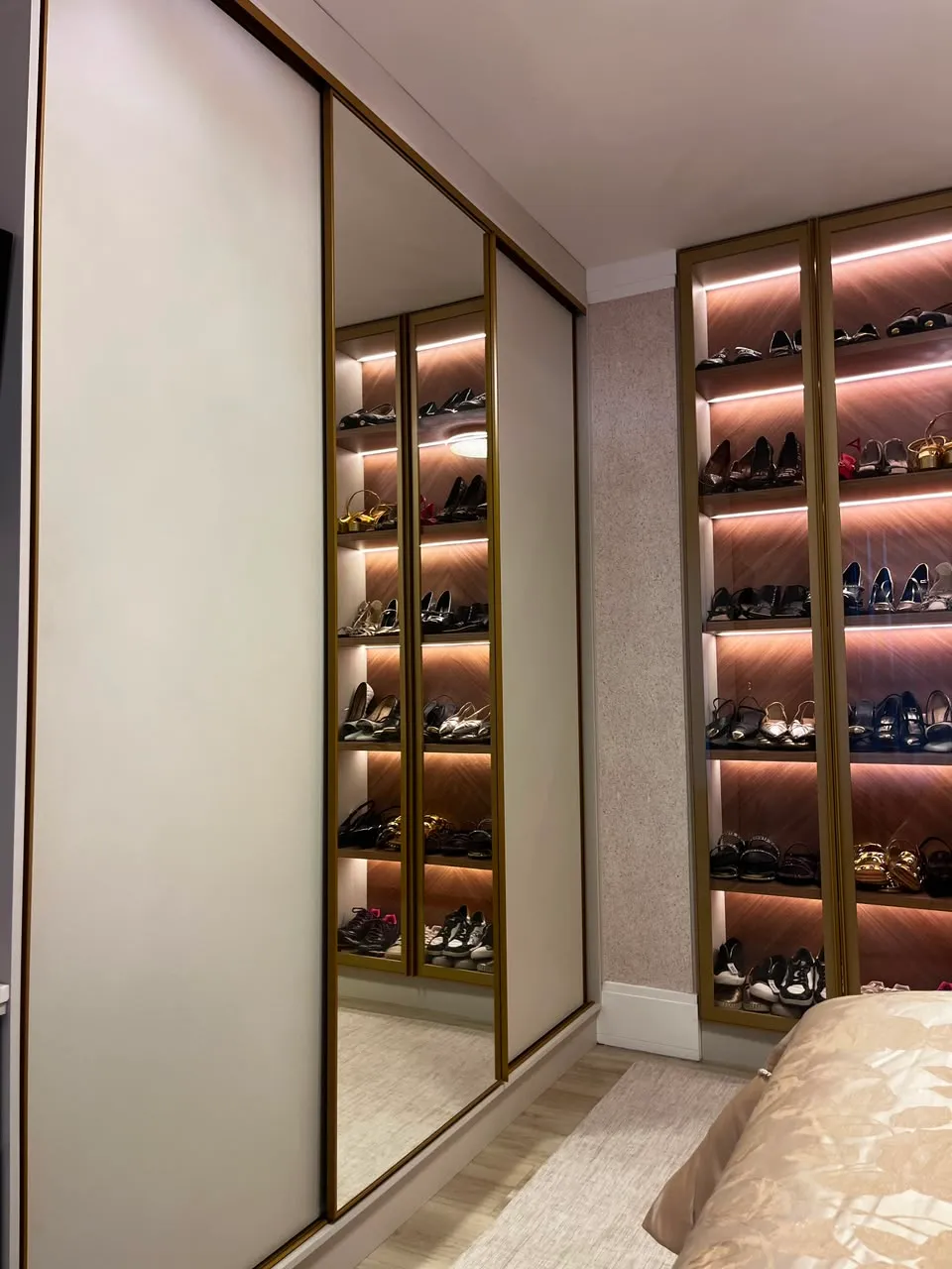 Closet planejado com portas espelhadas e friso dourado