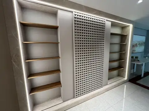 Porta de correr perfurada em padrão geométrico entre módulos de prateleiras