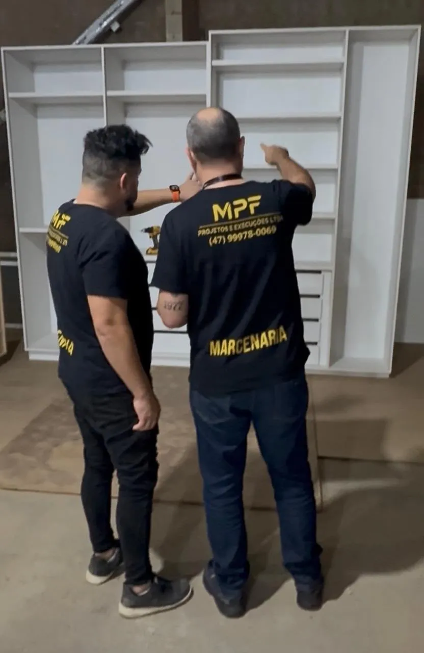 Instalação de estrutura suspensa com estrutura dourada sobre bancada de cozinha em obra