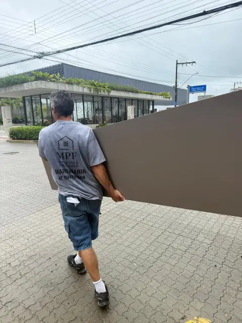 Profissional da equipe MPF transportando painel de marcenaria em via pública