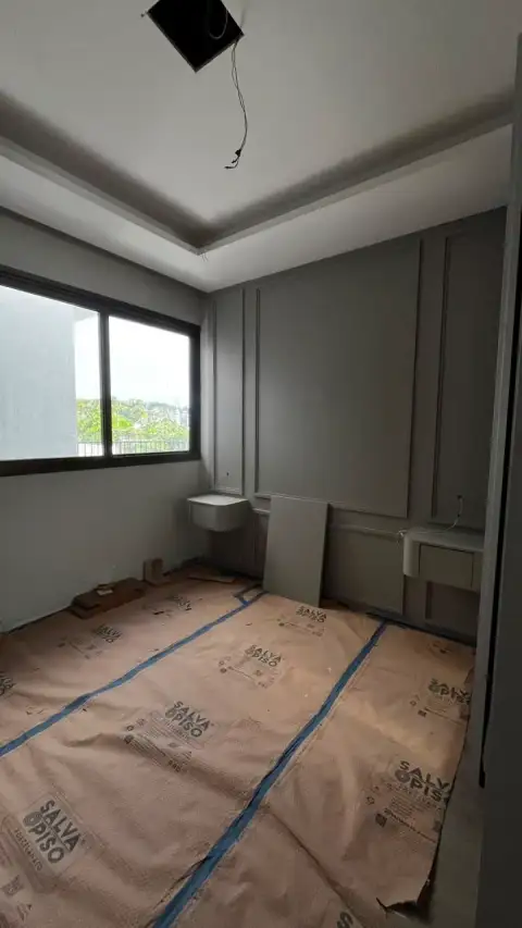 Sala em obra com proteção de piso, painéis de parede e portas de vidro para varanda