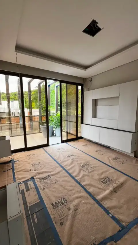 Sala em obra com nicho de painel de TV e portas de vidro para área externa