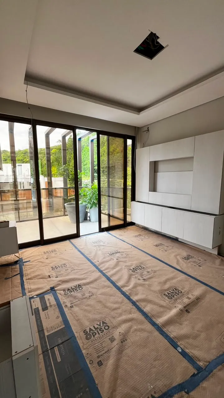 Sala em obra com nicho de painel de TV e portas de vidro para área externa