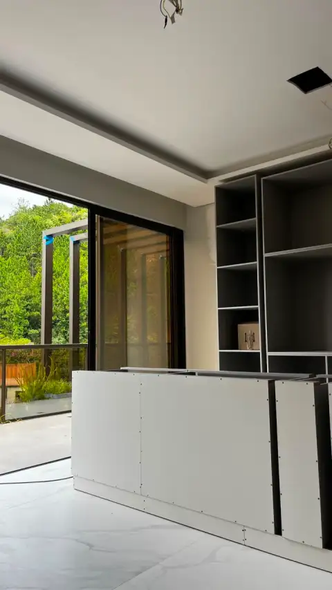 Bancada planejada em fase de montagem com estante ao fundo em ambiente em obra
