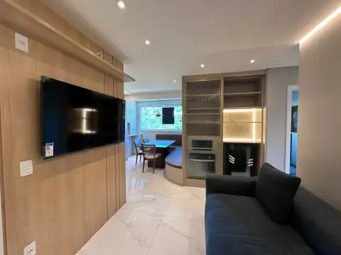 Sala integrada com painel de TV em madeira, iluminação em fita de LED e sofá azul