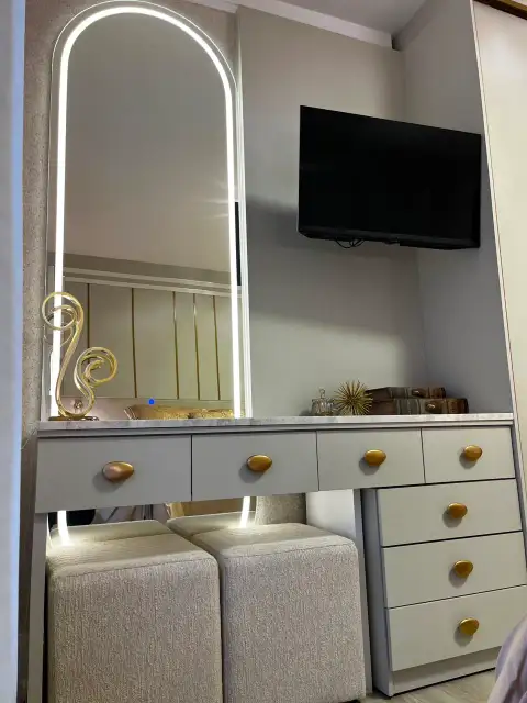 Sala de estar com painel de TV em mármore e ripado de madeira sob luminária circular dourada