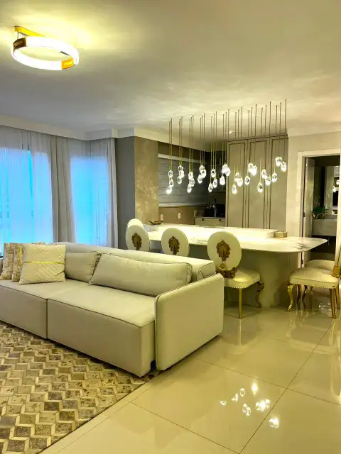 Sala de estar com bancada gourmet, lustre de cristais e poltronas estofadas douradas